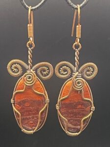 Red rainbow jasper with striking colours and metallic banding within hand-wrapped copper wire earrings featuring intricate spirals