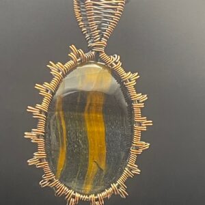 Hand-wrapped copper wire pendant featuring an oval cabochon of shimmering tiger's eye in rich honey and dark brown tones.